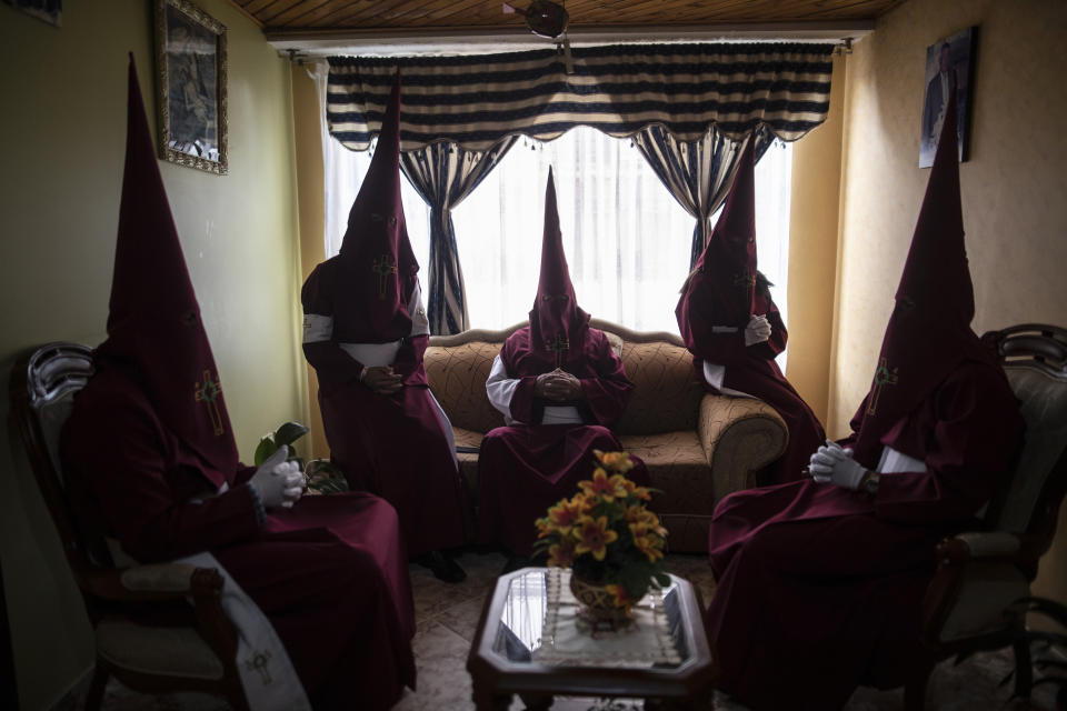 Members of the Nazarene brotherhood sit in a living room as they wait to take part in a Good Friday procession in Zipaquira, Colombia, on April 15, 2022. (AP Photo/Ivan Valencia)