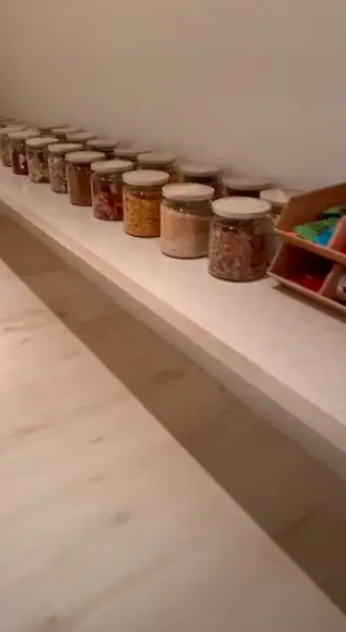 Inside Kim's pantry, a single shelf holds rows of giant clear glass jars in which can be seen all manner of snacks