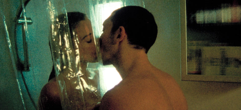 A man and a woman kiss through a shower curtain