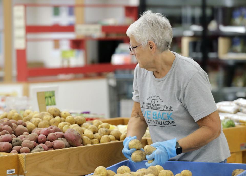 Volunteer Barb Williams stocks the produce section of the Oshkosh Area Community Pantry on Wednesday, Sept. 28, 2022, in Oshkosh, Wis.