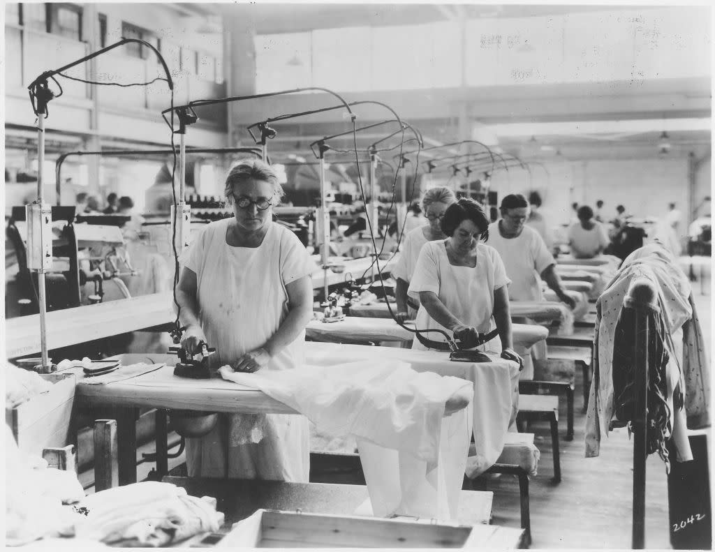 Photograph of laundry workers doing hand ironing in an industrial setting, 1920. Image courtesy US National Archives.