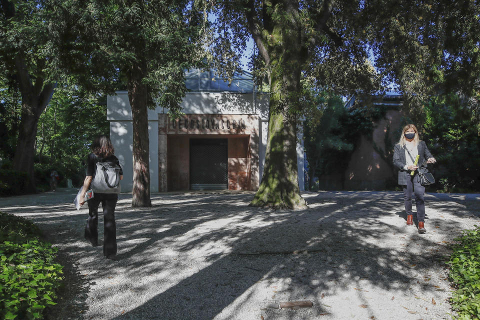 People walk past a closed pavilion during a press preview of the exhibition "How will we live together?", at the Biennale International Architecture, in Venice, Italy Thursday, May 20, 2021. The 17th International Architecture Exhibition opens Saturday after a one-year pandemic delay, during which time architecture has emerged as one of the key disciplines in the global coronavirus response. (AP Photo/Alessandra Tarantino)