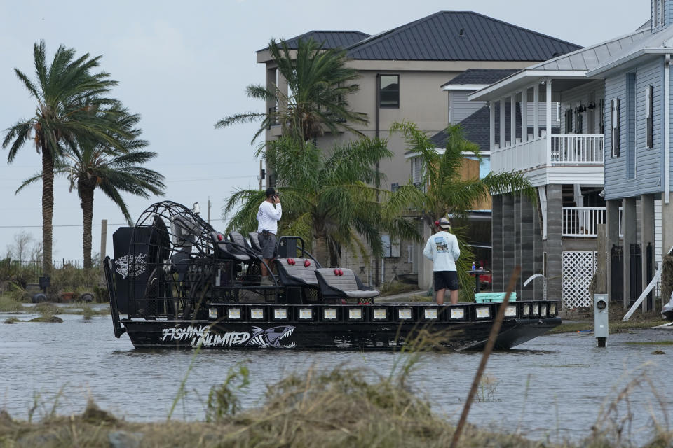 In the aftermath of Hurricane Ida, people on a airboat survey the damage to homes Wednesday, Sept. 1, 2021, in Myrtle Grove, La. (AP Photo/Steve Helber)
