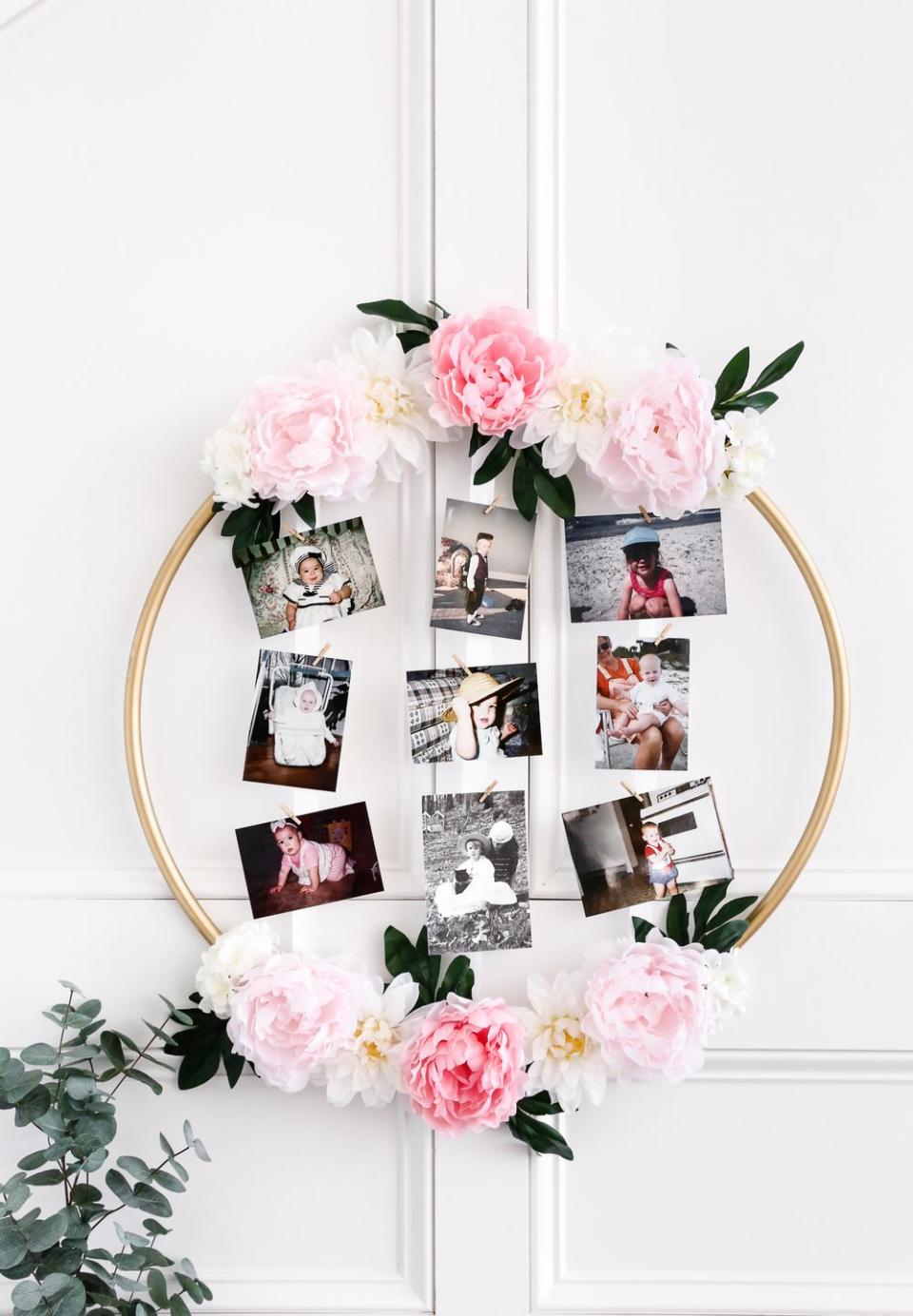 a hula hoop decorated with flowers holds a grid of baby photos, a great baby shower idea