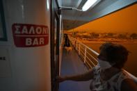 People use a ferry to evacuate from Pefki village on Evia island, about 189 kilometers (118 miles) north of Athens, Greece, Sunday, Aug. 8, 2021. Pillars of billowing smoke and ash are blocking out the sun above Greece's second-largest island as a days-old wildfire devours pristine forests and triggers more evacuation alerts. (AP Photo/Petros Karadjias)