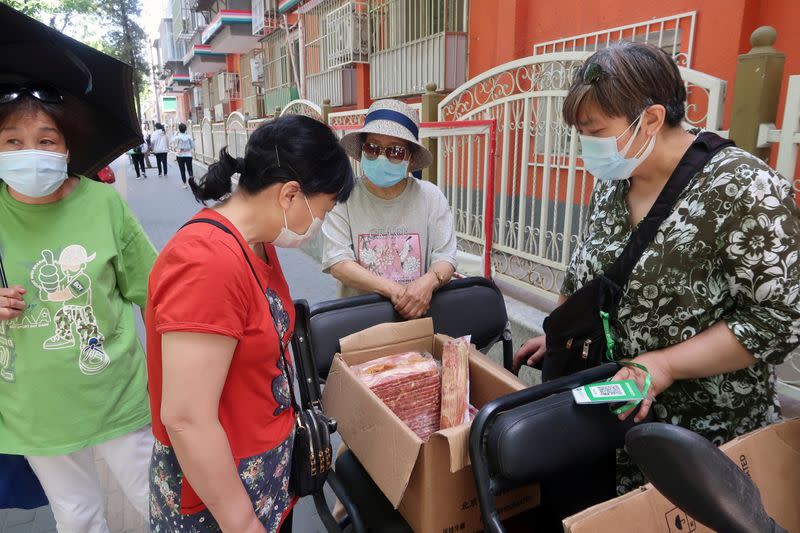 Street vendor Shan Peng attends to customers at her food stall set up on an electric tricycle outside a residential compound in Beijing