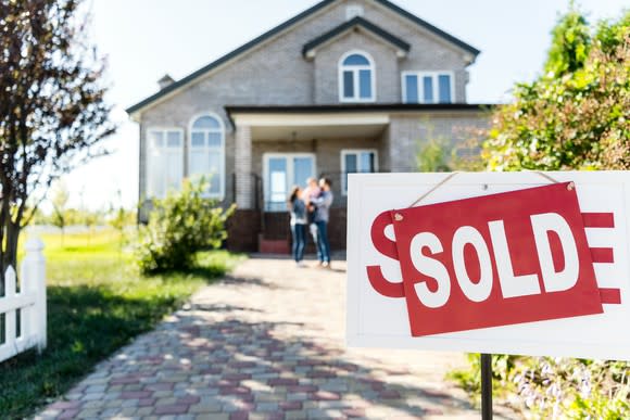 A SOLD sign sits outside a house.