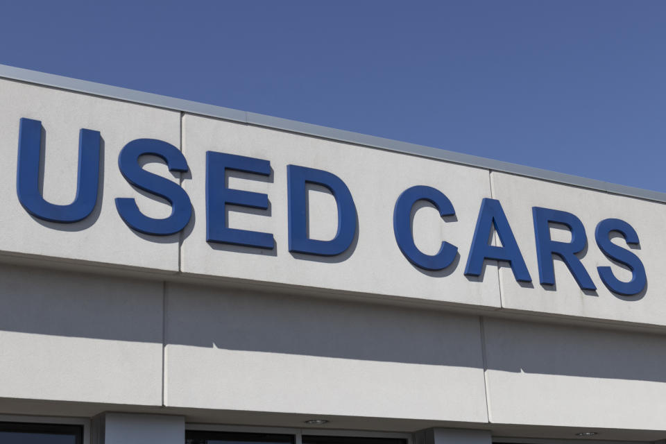 Sign with text "USED CARS" on the facade of a building against a clear sky