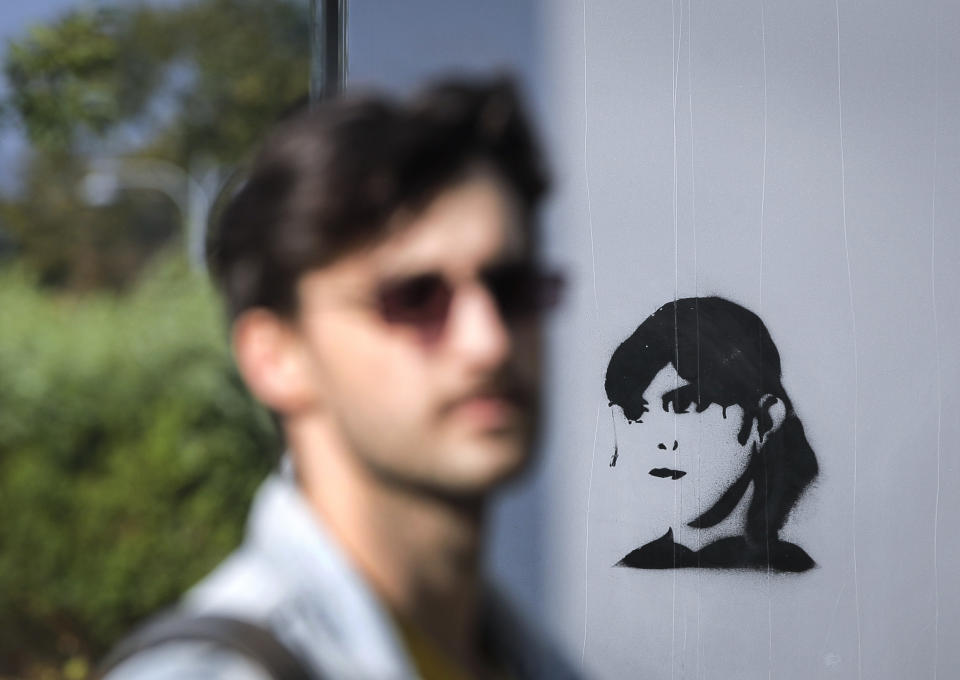 In this photo taken on Sunday, Oct. 6, 2019, a man walks by a stencil depicting Laura Codruta Kovesi, Romania's former chief anti-corruption prosecutor, in Bucharest, Romania. For Romania’s Laura Codruta Kovesi, opposition to her successful candidacy to become the European Union’s first chief prosecutor came from a familiar source - her own country’s government. Kovesi spent five years as head of the Romanian Anticorruption Directorate and those indicted by her office included 14 Cabinet members, 53 lawmakers and a member of the European Parliament. (AP Photo/Vadim Ghirda)