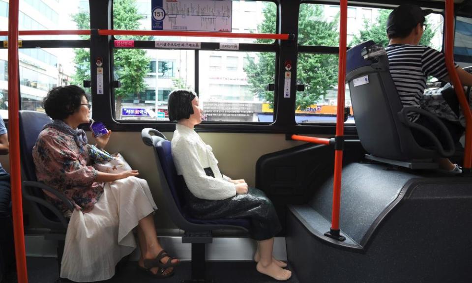 A statue of a teenage girl pictured on a bus running through downtown Seoul.