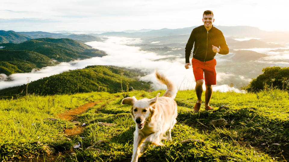 A man running up a mountain with his dog