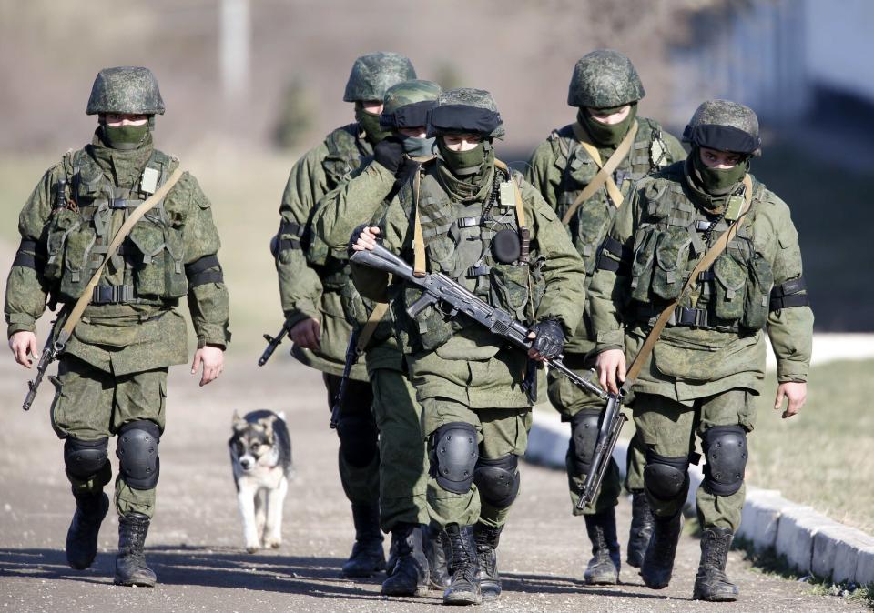 Armed men believed to be Russian servicemen march outside a Ukrainian military base in the village of Perevalnoye