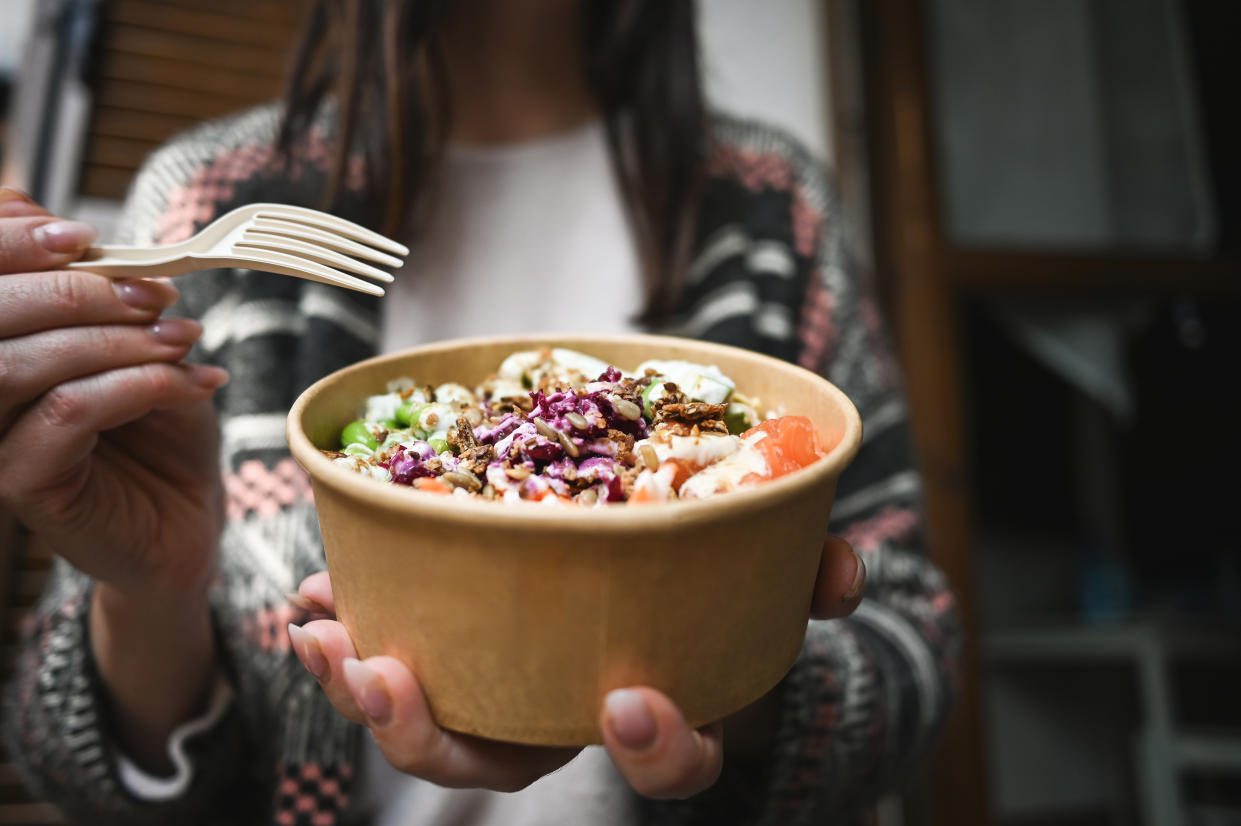 Close up of a woman eating poke with fork at home.