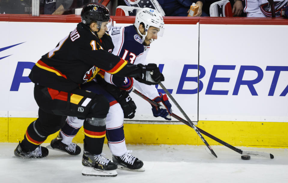 Columbus Blue Jackets forward Johnny Gaudreau, right, is checked by Calgary Flames forward Mikael Backlund during second-period NHL hockey game action in Calgary, Alberta, Monday, Jan. 23, 2023. (Jeff McIntosh/The Canadian Press via AP)