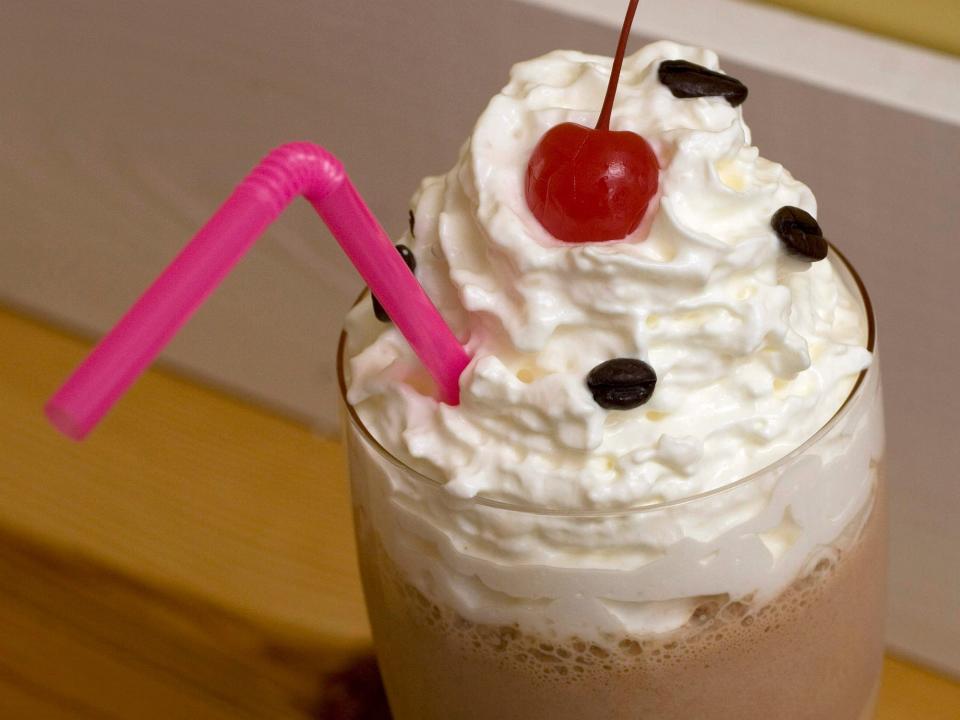 milkshake with whipped cream and a cherry and a pink straw
