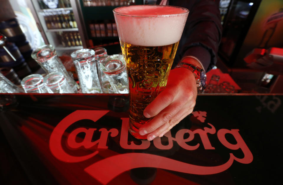 A bartender holds a glass of Carlsberg beer in a bar in St. Petersburg June 17, 2014. Denmark's Carlsberg will keep its breweries in Russia running regardless of empty capacity, despite other brewers closing plants as Western sanctions over Ukraine hamper an already faltering economy. To match Interview CARLSBERG-RUSSIA/      REUTERS/Alexander Demianchuk (RUSSIA - Tags: BUSINESS)