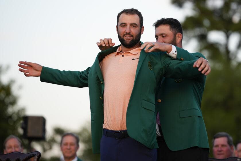 Jon Rahm, of Spain, puts the green jacket on winner Scottie Scheffler after the Masters.