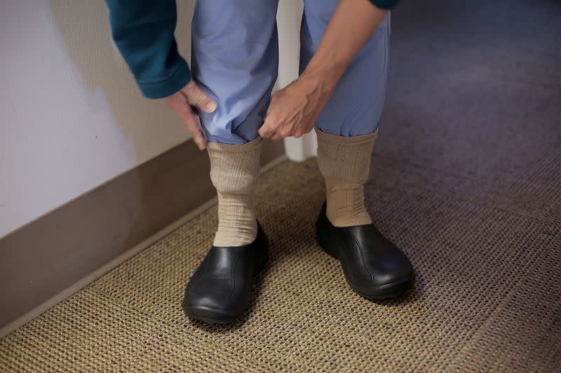 A nurse from Harborview Medical Center's home assessment team wears easily cleanable shoes and tucks her scrubs into her socks while preparing to visit the home of a person potentially exposed to novel coronavirus at Harborview Medical Center in Seattle