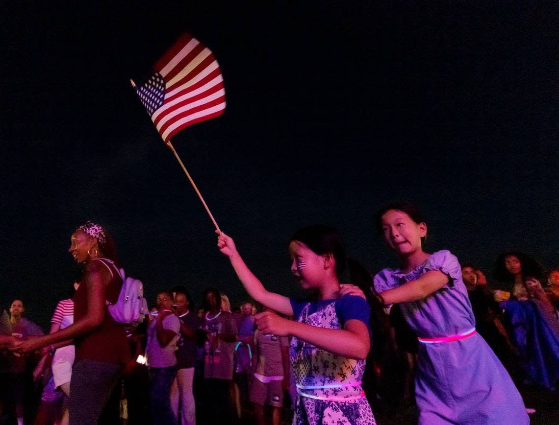 Riyoon Kwon, 8, holds an American flag aloft while dancing with her sister, Jaeyoon Kwon, 11, during an Independence Day celebration at Dorothea Dix Park on Tuesday, July 4, 2023, in Raleigh, N.C. Kaitlin McKeown/kmckeown@newsobserver.com