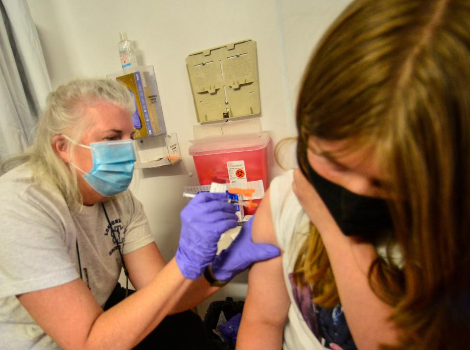 Laurie Gayda, a vaccinator with Rescue Inc., gives Lola McGinnis, 12, of Bellows Falls, Vt., the first dose of the Pfizer COVID-19 vaccine as her sister, Lola, 12, waits for her shot on Monday, May 24, 2021. Rescue Inc. hosted a dual COVID-19 vaccine clinic at the Bellows Falls Fire Department, in Bellows Falls, Vt. People could get a scheduled dose of the Pfizer vaccine or go to the walk-in Johnson & Johnson clinic. (Kristopher Radder/The Brattleboro Reformer via AP)