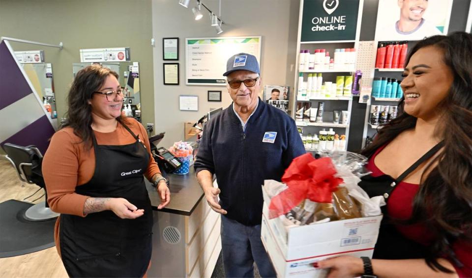 Great Clips hair stylists Jasmine Delgadillo, left, and Karen Sam, right, give a gift to Dave Costa as he delivers the mail at McHenry Village in Modesto, Calif., Wednesday, Dec. 27, 2023. Costa is retiring Wednesday after more than 56 years with the Postal Service.
