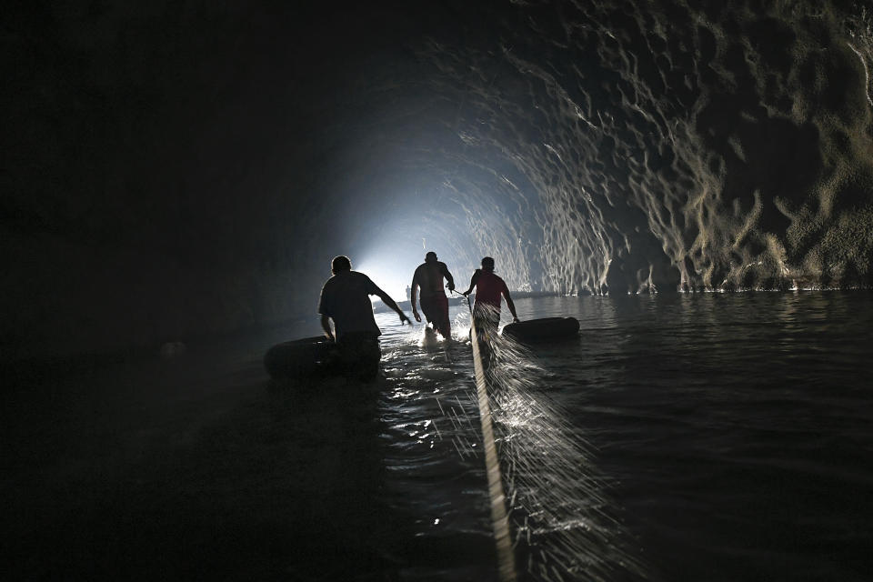 Men, equipped with inner tubes, wade through an abandoned highway tunnel with the aid of a safety line as they work to repair a self-created water system in the Esperanza neighborhood of Caracas, Venezuela, Thursday, June 11, 2020. Water service in Venezuela has gotten so bad that poor neighborhoods have started to rig private water systems or hand dig shallow wells. (AP Photo/Matias Delacroix)