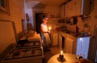 FILE PHOTO: Samira Hanna,70, walks in her kitchen as she holds a candle due to a power cut, in Beirut