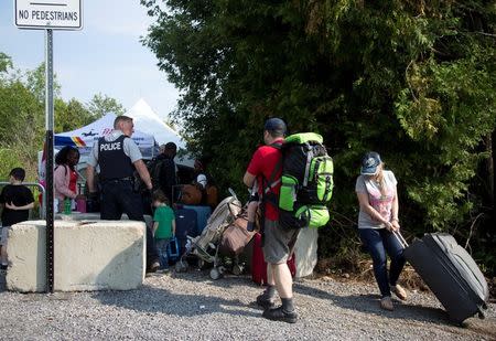 A Syrian family gets in line behind a group from Haiti to be processed after crossing the U.S.-Canada border into Canada from Champlain, New York, U.S., August 3, 2017. REUTERS/Christinne Muschi