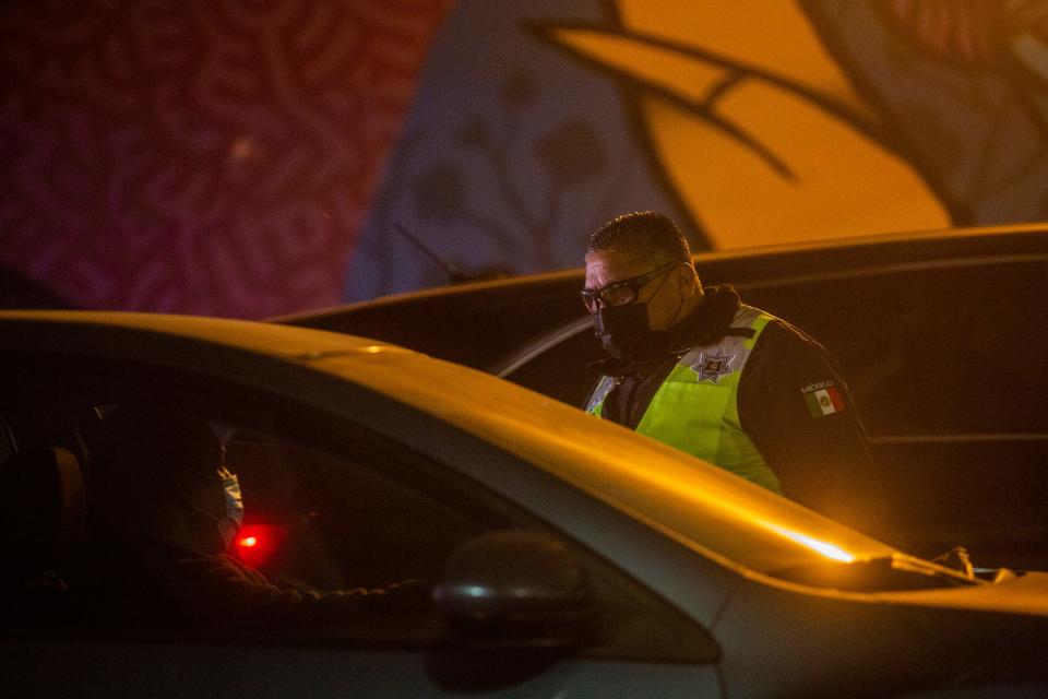 A municipal police officer for the Mexican border city of Mexicali mans a "sanitary filter" for U.S. nationals coming into Mexico on Dec. 18, 2020, as part of an attempt to slow the spread of COVID-19 in the border communities in the Imperial County region in the U.S. and Baja California, Mexico.