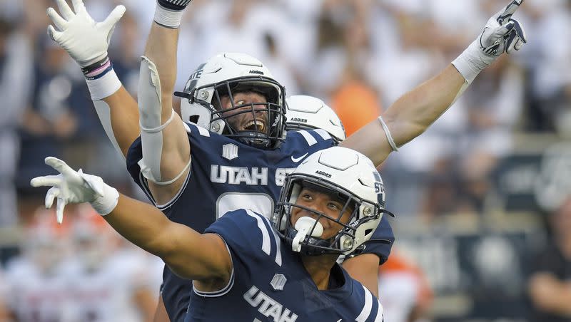 Utah State linebacker Bronson Olevao Jr. (14) and defensive end Paul Fitzgerald celebrate after Idaho State fumbled the ball during the first half of an NCAA college football game Saturday, Sept. 9, 2023, in Logan, Utah. 