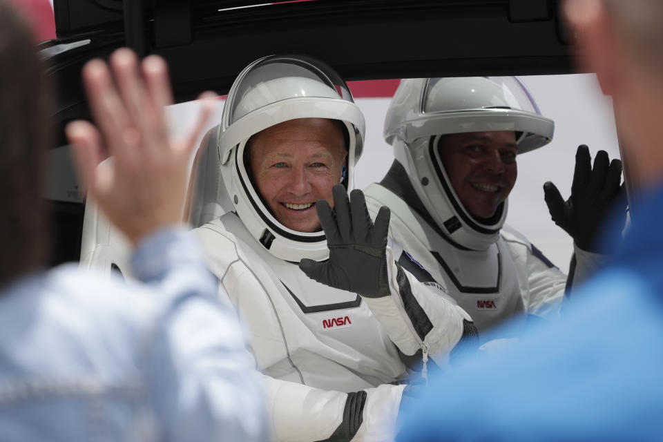 NASA astronauts Douglas Hurley, left, and Robert Behnken ride a Tesla SUV from the Neil A. Armstrong Operations and Checkout Building on their way to Pad 39-A, at the Kennedy Space Center in Cape Canaveral, Fla., Wednesday, May 27, 2020. The two astronauts will fly on a SpaceX test flight to the International Space Station. For the first time in nearly a decade, astronauts will blast into orbit aboard an American rocket from American soil, a first for a private company. (AP Photo/John Raoux)