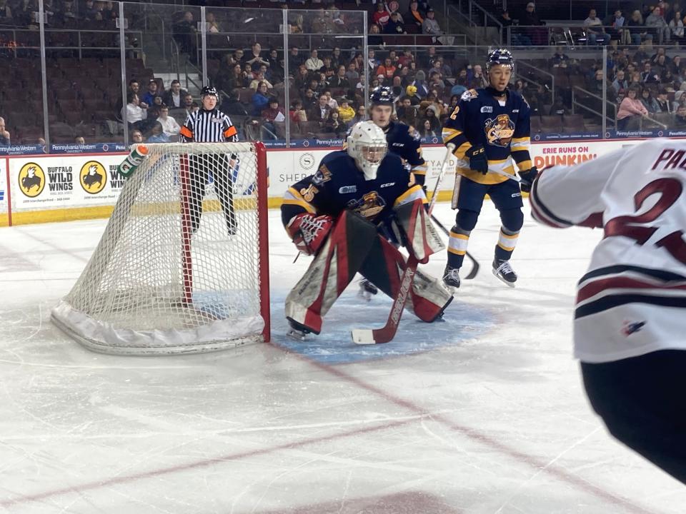 Erie Otters goaltender Charlie Burns, backed up by defensemen Ty Henry (2) and Alexis Daviault, prepares to stop a shot by Guelph's Charlie Paquette during the first period of the teams' Feb. 1, 2024, Ontario Hockey League game at Erie Insurance Arena. Erie won 3-0.
