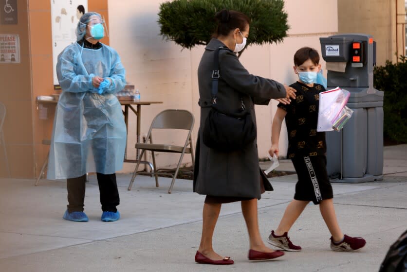 EL SERENO, CA - JANUARY 4, 2022 - - A youngster prepares to be tested for COVID-19 at a walk-up test site at the El Sereno Middle School in the El Sereno neighborhood in Los Angeles on January 4, 2022. Students were accompanied by their parents. The Los Angeles school district has ordered coronavirus tests for all students and staff before they return from winter break next week as a new period of high anxiety takes hold among parents and educators amid the explosive surge of the Omicron variant. (Genaro Molina / Los Angeles Times)