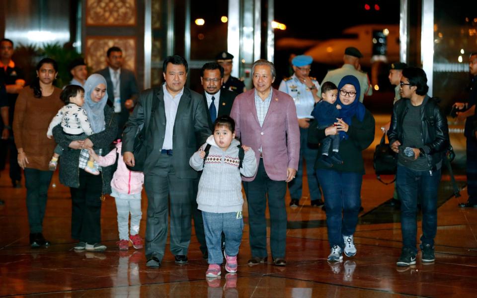 Malaysians walk with Foreign minister Anifah Aman, centre right, after arriving at Kuala Lumpur airport - AP