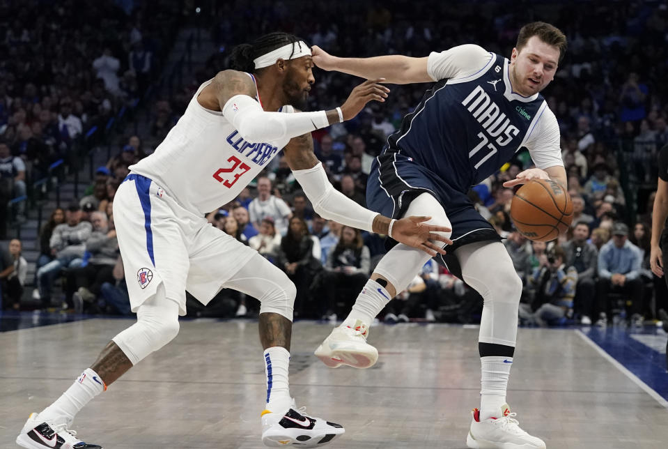 Dallas Mavericks guard Luka Doncic (77) loses his balance while dribbling against Los Angeles Clippers forward Robert Covington (23) during the second half of an NBA basketball game in Dallas, Sunday, Jan. 22, 2023. (AP Photo/LM Otero)