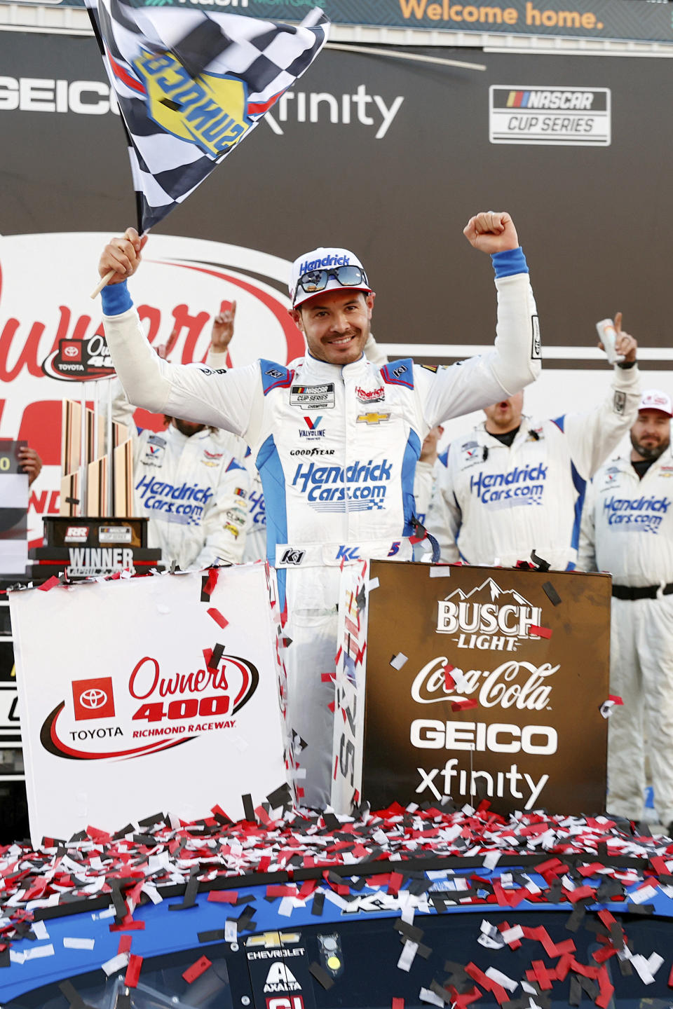 Kyle Larson, center, poses for the media a second time after he was engulfed in confetti the first time while celebrating in Victory Lane after his win in a NASCAR Cup Series auto race at Richmond Raceway on Sunday, April 2, 2023, in Richmond, Va. (Eva Russo/Richmond Times-Dispatch via AP)