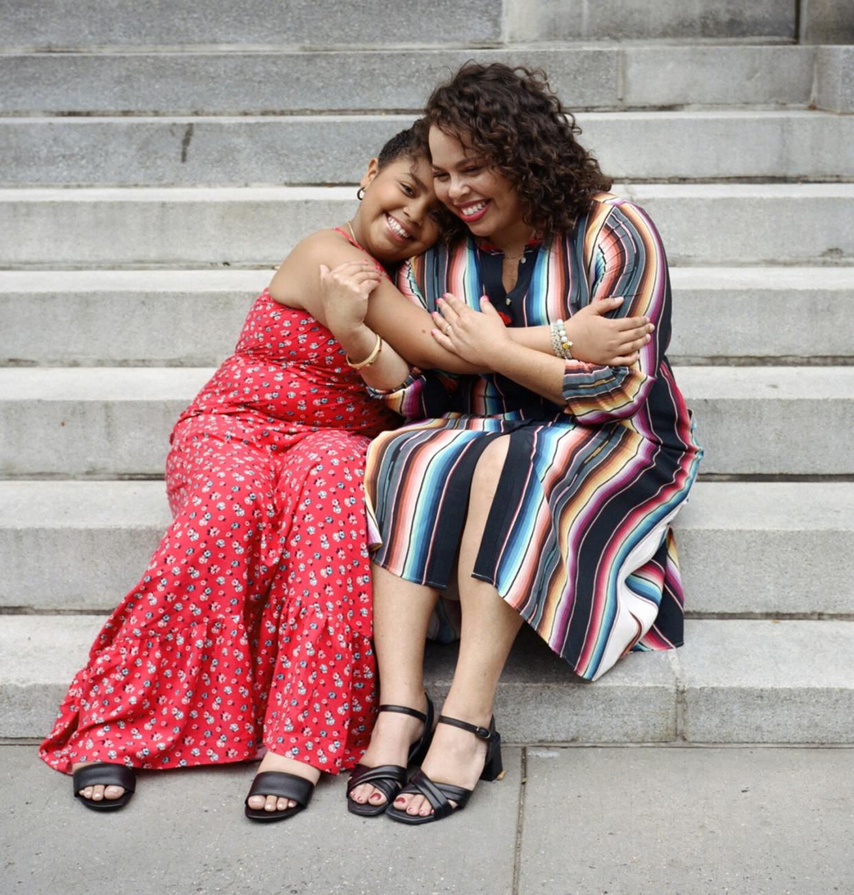 two women sit on steps hugging