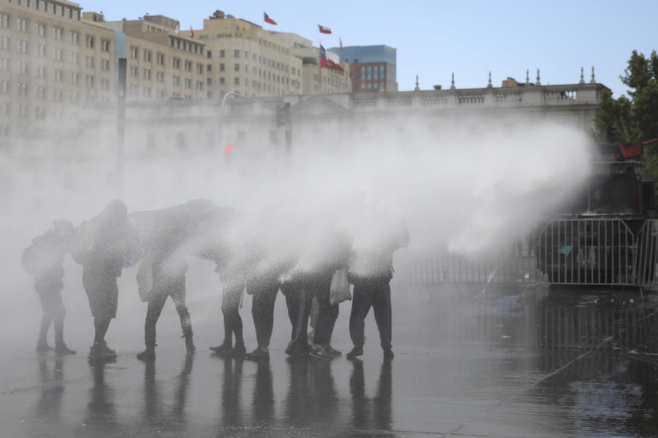 A police water cannon sprays anti-government demonstrators in front of La Moneda presidential palace in Santiago, Chile, Friday, Nov. 1, 2019. Groups of Chileans continued to protests as government and opposition leaders debated the response to nearly two weeks of protests that have paralyzed much of the capital and forced the cancellation of two major international summits. (AP Photo/Rodrigo Abd)
