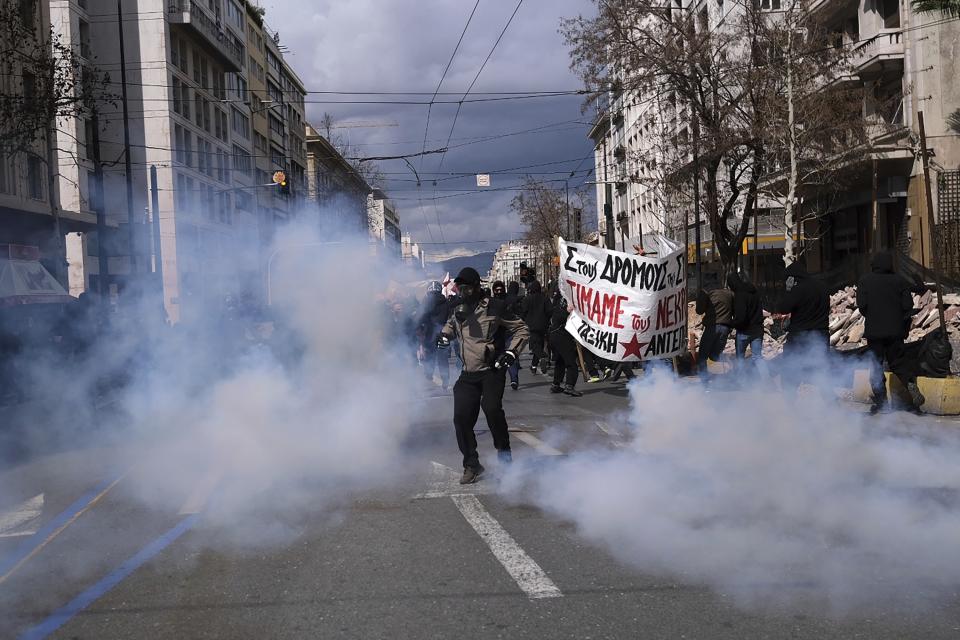 A demonstrator kicks back a tear gas canister to riot police during clashes in Athens, Greece, Sunday, March 5, 2023. Thousands protesters, take part in rallies around the country for fifth day, protesting the conditions that led the deaths of dozens of people late Tuesday, in Greece's worst recorded rail accident. (AP Photo/Aggelos Barai)