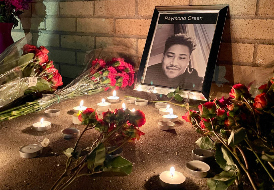 A framed photo of victim Raymond Green Vance is seen surrounded by candles and flowers during a vigil.