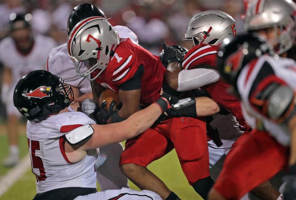 East running back Ziaire Stevens, center, pushes through Canfield defensive lineman Vince Luce during the first half of a Division III playoff football game, Friday, Oct. 27, 2023, in Akron, Ohio.