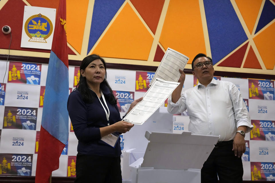 Election workers holds up ballots as manual counting begins after polls close for parliamentary elections in Ulaanbaatar, Mongolia in the early hours of Saturday, June 29, 2024. Preliminary results were expected by early Saturday morning after voting ended at 10 p.m. Friday across the vast but sparsely populated country squeezed between China and Russia, two much larger authoritarian states. (AP Photo/Ng Han Guan)