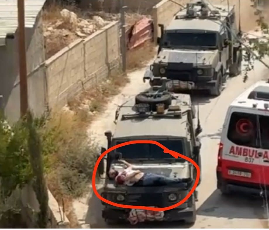 以色列 22 日在約旦河西岸的杰寧市展開軍事行動，但卻將一名受傷的巴勒斯坦男子綁在軍車引擎蓋上離去，疑似使用「人盾」的行徑引發廣泛討論。   圖：翻攝自 @BasemSaabneh X 帳號