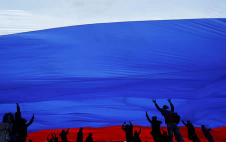 FILE PHOTO: People hold a giant Russian national flag during a festive concert marking the second anniversary of Russia's annexation of the Crimea region, in Red Square in central Moscow, Russia March 18, 2016. REUTERS/Maxim Shemetov/File Photo