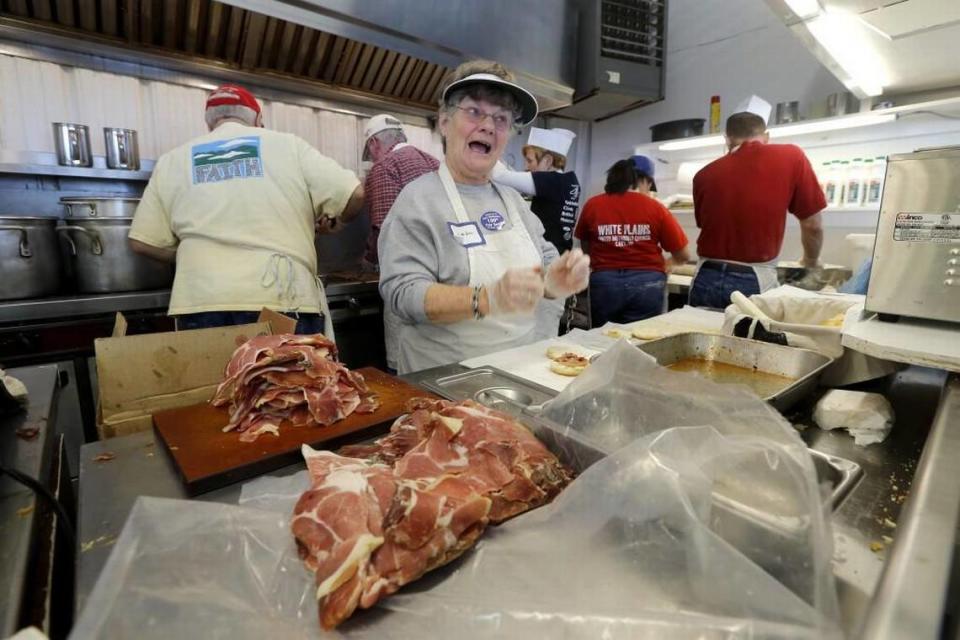 Linda Huffman puts ham inside biscuits and smiles at a customer at the NC State Fair booth operated by The First United Methodist Church of Cary and White Plains United Methodist Church on Monday, Oct. 19, 2015.