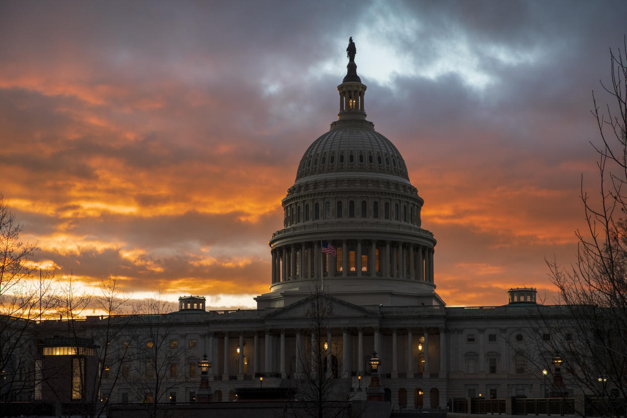 U.S. Capitol building against an orange, cloudy sky.