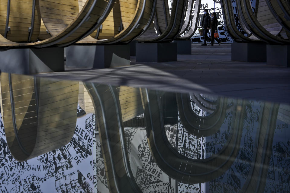 Women walk by a reflected art installation at an outdoor shopping mall in Beijing, Sunday, Feb. 25, 2024. (AP Photo/Andy Wong)