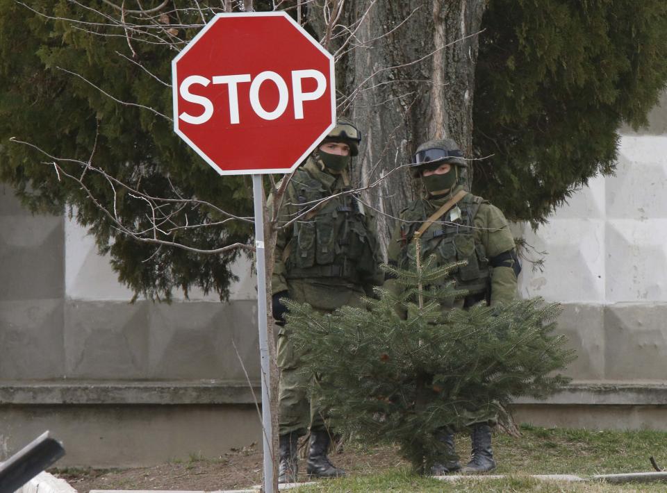 Military personnel, believed to be Russian servicemen, stand outside the territory of a Ukrainian military unit in the village of Perevalnoye outside Simferopol, March 4, 2014. President Vladimir Putin has ordered troops that took part in military exercises in central and western Russia to return to base after completing their training, Russian news agencies quoted the Kremlin spokesman as saying on Tuesday. REUTERS/David Mdzinarishvili (UKRAINE - Tags: POLITICS MILITARY)