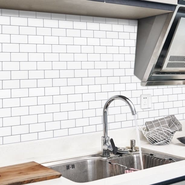 Modern kitchen with stainless steel faucet, subway tile backsplash, and natural wood cutting board