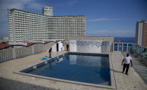 Los trabajadores realizan tareas de mantenimiento en la piscina de la azotea del Hotel Capri durante un encierro que afecta al turismo para frenar la propagación de la pandemia COVID-19 en La Habana, Cuba, el miércoles 17 de junio de 2020. (AP Foto/Ismael Francisco)